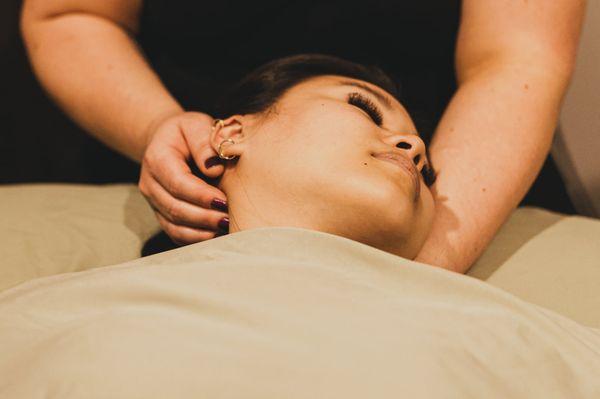 A sports massage therapist works on a client's neck.