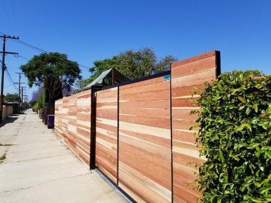 Horizontal redwood fence and sliding gate built with tongue and groove panels for a resident's alleyway entrance.