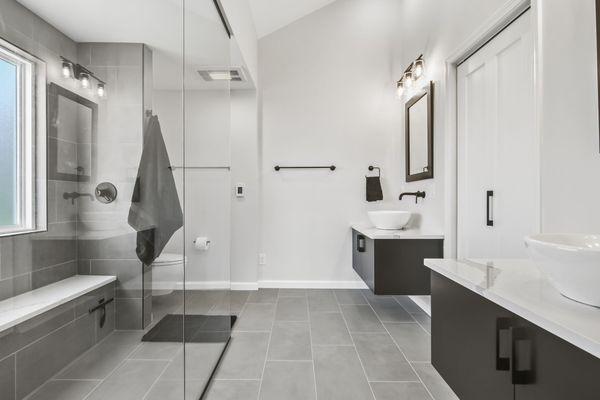 Modern master bath remodel at Lake Springfield. Tiled shower, built in bench, linear drain, doorless entry. Floating vanities, vessel sinks.