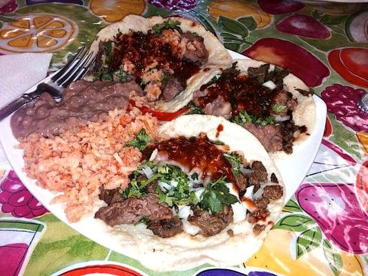 Tacos de lengua y de carne asada, con arroz tradicional y frijoles refritos al lado.