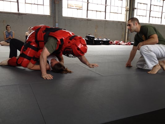 A class participant works on her ground technique against instructor Gershon Ben Keren (in the "Red Man" suit)