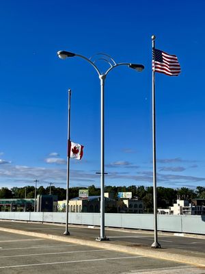 Canadian and US flags on the poles near other end of the bridge.