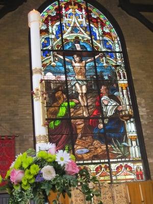 The Paschal candle and the main stained-glass window, at Easter.