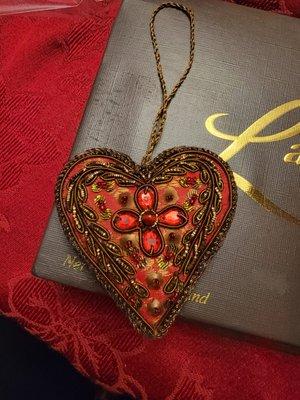 An embroidered heart ornament used in gift baskets, on wine bottles, for wrapping packages.