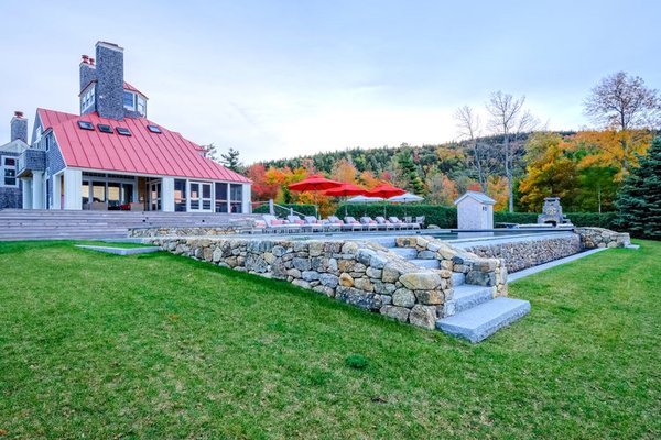 Fieldstone retaining wall, granite steps with stone veneered infinity edge swimming pool