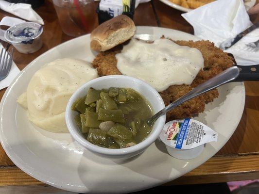 Chicken fried steak, mashed potatoes, green beans and a hard dinner roll