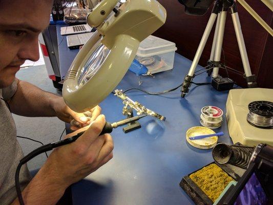 Dalton soldering a proprietary power button.