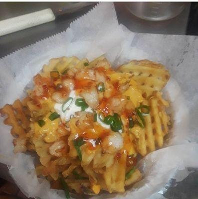 Spunky Fries  are Waffle Fries with Cheese Sauce topped with Sour Cream, Shrimp Bites and drizzled with our Special Spunk Sauce.