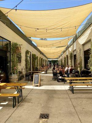 Outdoor seating. Good for pets, parents, and kids. Brewery on the right. Coffee, food, wine, and crafts on the left.