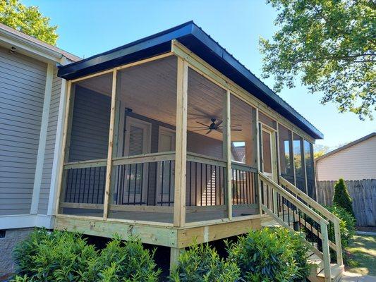 Screened in deck with TV wall, T&G ceiling, recessed lights, ceiling fan, and aluminum balusters.