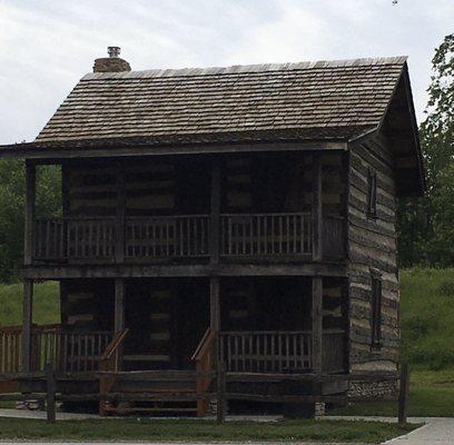 A restored 1800s cabin is across the street from the park sign.