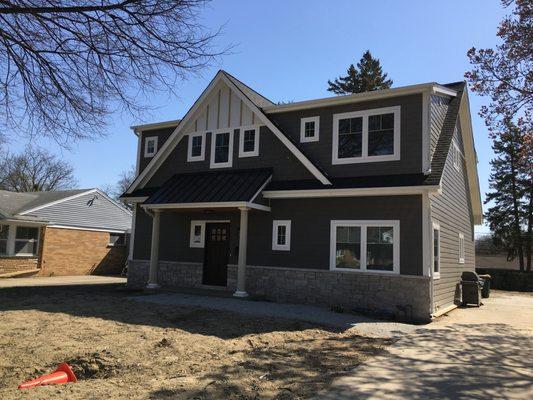 Modern craftsman style exterior with metal roof and stone accents.