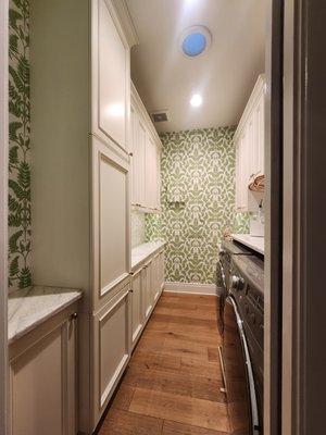 Beautiful laundry room with custom cabinets, marble countertops and wallpaper.