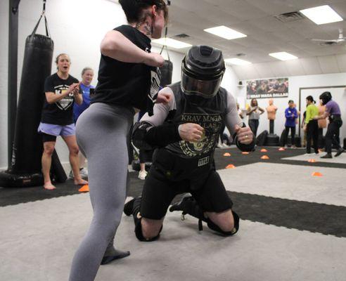 A student fighting back against and armored attacker at the end of one of our Women's Empowerment Seminars.