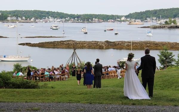 Here comes the bride, escorted by her father, down the waterfront lawn for her wedding at Harborfields