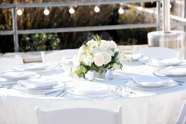 Bright white and simply elegant table settings greet guests beach side.