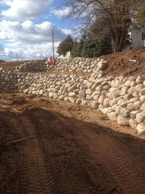 Granite Fieldstone boulders 12-18" in diameter.  Lower wall is 
 4.5-5' high.  Fieldstone provides a cost effective solution ...