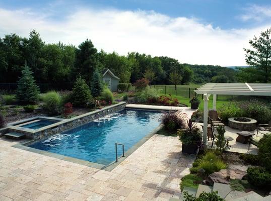 Soothing water fall effects add peaceful sound and aesthetics to this inground pool design.