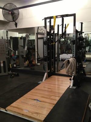 Olympic Lifting Platform and high performance squat rack include gymnastic rings and TRX and bumper plates.