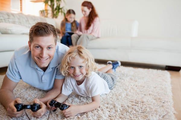 Father and son playing video games on area rug