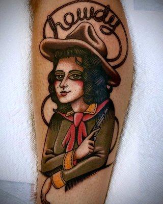 "Howdy" in rope above a cowgirl with a gun tattoo