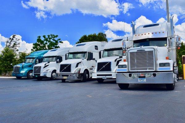 Status Transportation owner operator trucks on a bright and sunny day.