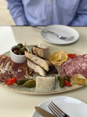 Cheese board , with dry prosciutto and burnt bread.