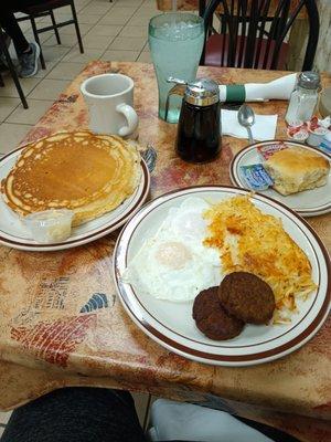 Two eggs over easy with crisp hash browns, Patty sausage, biscuit and one yummy pancake.