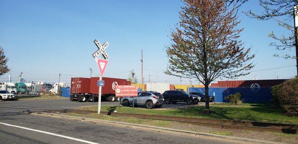 Parked & moving cars, a yard truck, dropped containers scattered about, parked containers adjacent to the dock doors, port shuttles constan