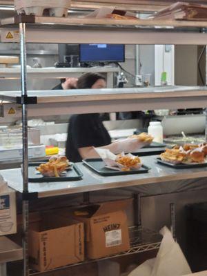 Back food service area. Condiment bottles in their sides and covered in sticky mess, old fries all over prep counter and floor.