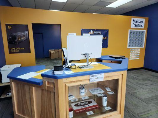 Front desk with business promotional items, commercial mailboxes in the background.