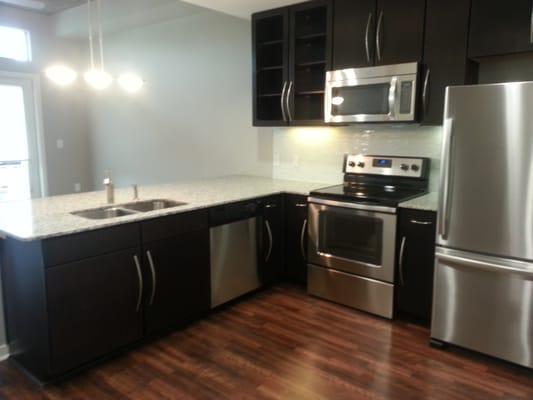 Spacious kitchens with stainless steel appliances and dark wood cabinets.