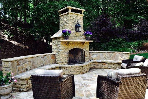 Stone patio with seating wall and wood burning fireplace.