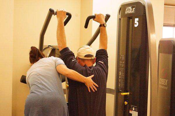 She corrects posture for using the machine.