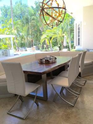 Wood log table with stainless base legs. Contemporary white leather chairs and designer chandelier.