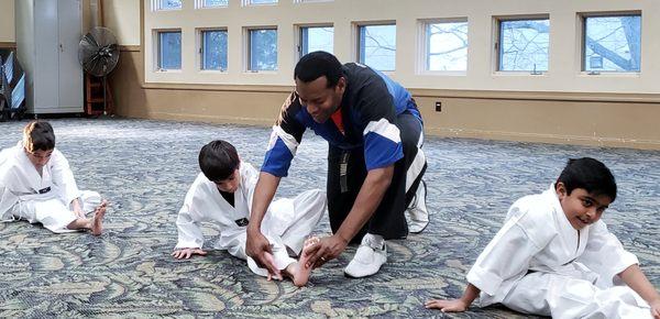 Master Maye helping a student with stretching.