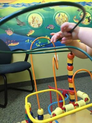 Baby examination room with toys and a mural.