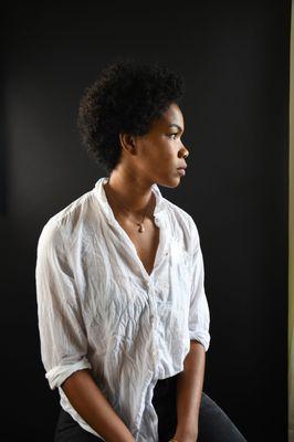 Woman staring into light with a white shirt on back backdrop