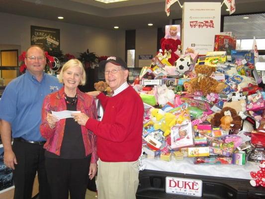 Eley Duke & Lydia Duke presenting Toys for Tots with a check and a truck full of toys. We collected over 550 toys!