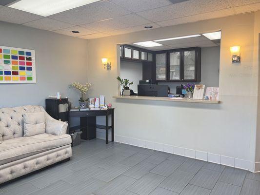 View of the receptionist desk, waiting room sofa, and water dispenser.