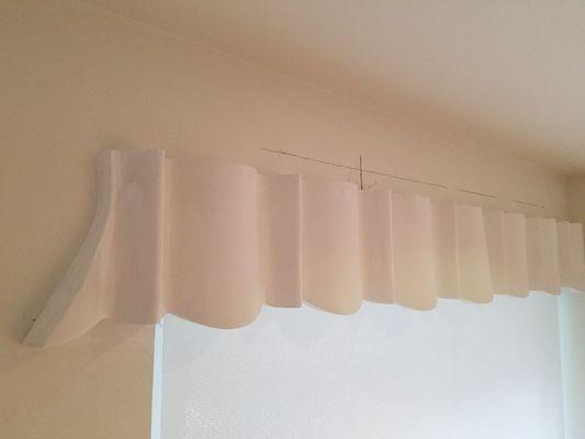 A plaster balance to hid window roll down shade.