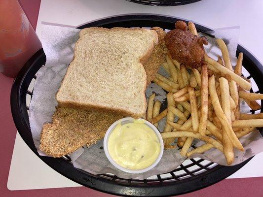 Catfish sandwich with homemade tartar sauce, hush puppy, and fries