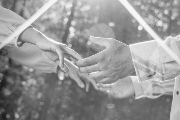 Couple touching hands, sun flare, black and white.