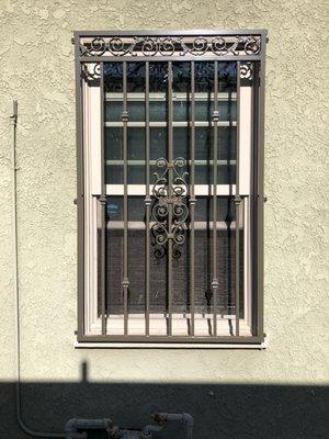 Iron window grilled with knuckles, cast iron designs across the top and center, powder coated