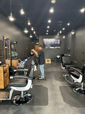 Inside of barbershop.  Owner, "shorty" giving a cut.