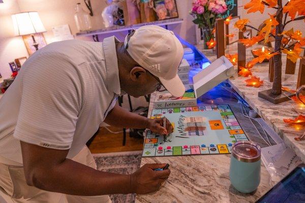 Mayor Cornelius  Huff signing Alli's On Main's INMANopoly!