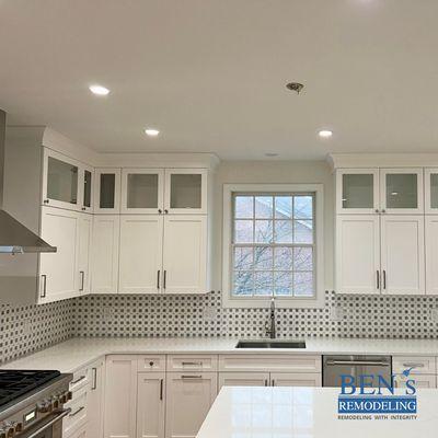 a remodeled kitchen with wooden floor, white cabinet, white cabinet island, white quartz countertop, recessed lighting