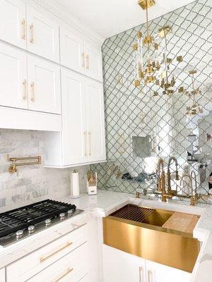 Aphrodite counters and white shaker cabinets gold faucet also from Gila