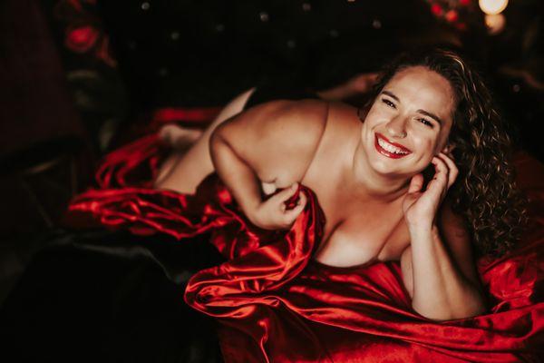 A gorgeous boudoir session paired with a smile! Model is wearing a tank top covered with a satin sheet. Timeless, Stunning!