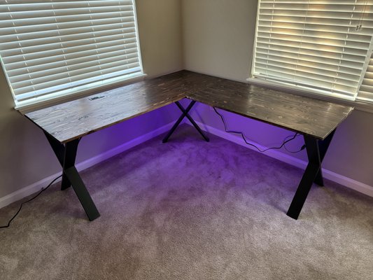 An awesome L-shaped desk complete with recessed outlets and modern x-shaped metal legs!